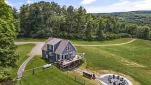 Une grande maison dotée d’une terrasse et d’un espace extérieur circulaire aménagé pour s’asseoir.