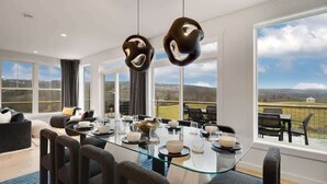 Un espace repas moderne avec une table en verre, des chaises noires et une vue panoramique grâce à de grandes fenêtres.
