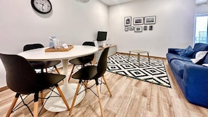 A modern meeting room with a round table, black chairs, a clock, and a wall-mounted air conditioner. - Stylish Apt Off The Sea Front (Il-Gzira)