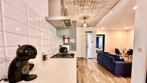 A modern kitchen with white tiles, a gas stove, and a coffee machine. - Stylish Apt Off The Sea Front (Il-Gzira)