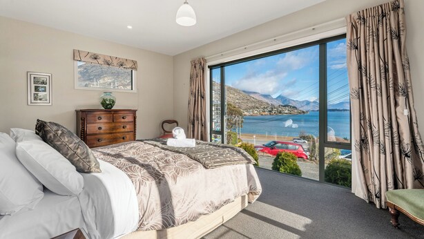 Une chambre avec un grand lit, une commode et une vue sur un lac et des montagnes.