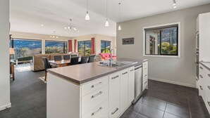 Une cuisine moderne dotée d’un îlot central, de meubles blancs et d’une grande fenêtre offrant une vue panoramique.