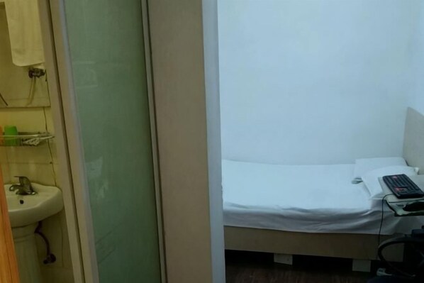 A room with a bed, a desk with a computer, and a sink. - Fushun Yuanxiang Hotel (Fushun)