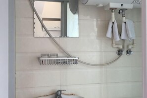 A bathroom with a shower, a mirror, and a towel rack.