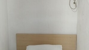 A single bed with a wooden headboard in a room with white walls. - Fushun Yuanxiang Hotel (Fushun)