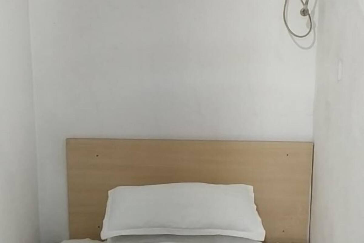 A single bed with a wooden headboard in a room with white walls.