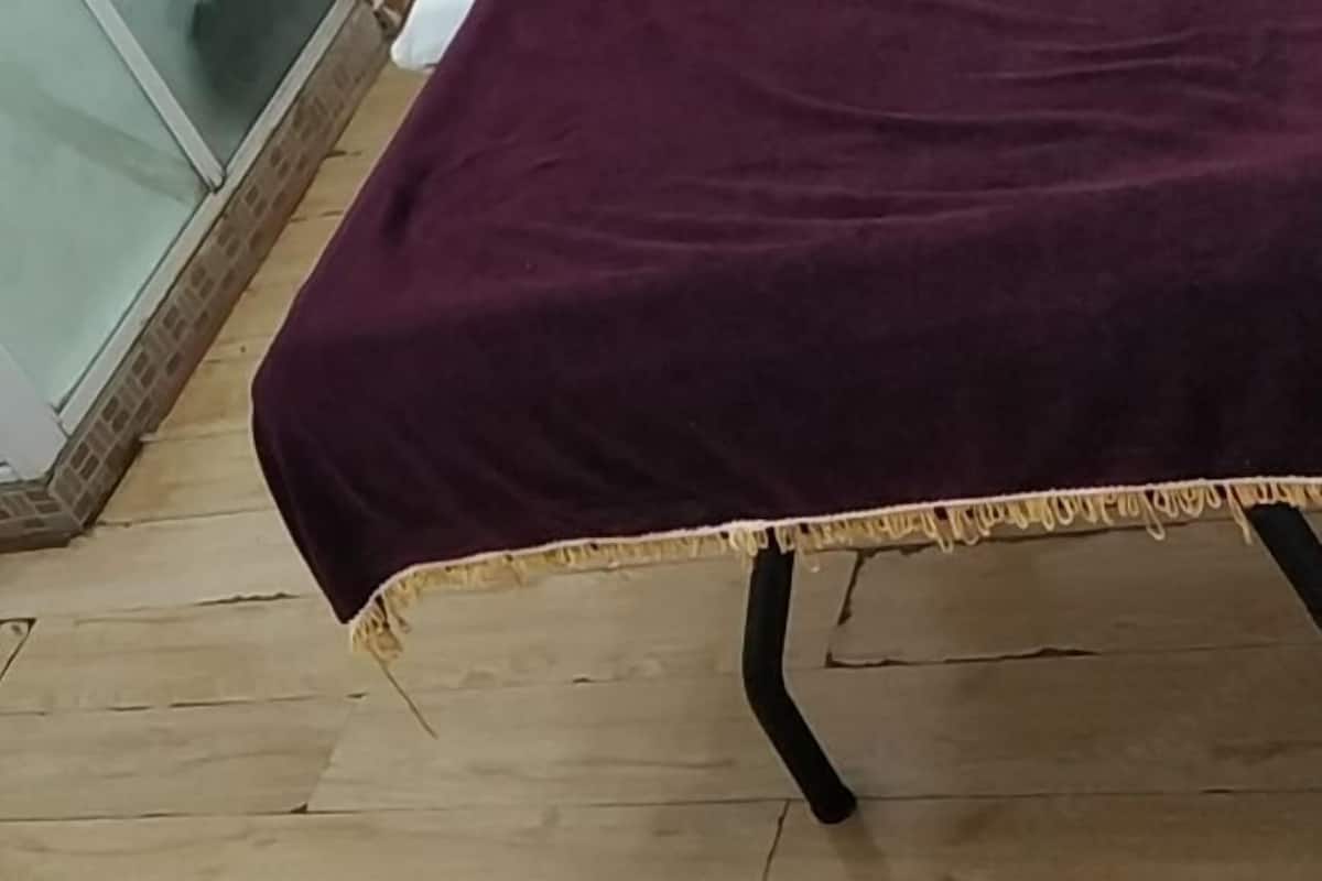 A room with a wooden floor, a purple bedspread, and a white wall.
