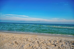 En sandstrand med blide bølger og en klar blå himmel.