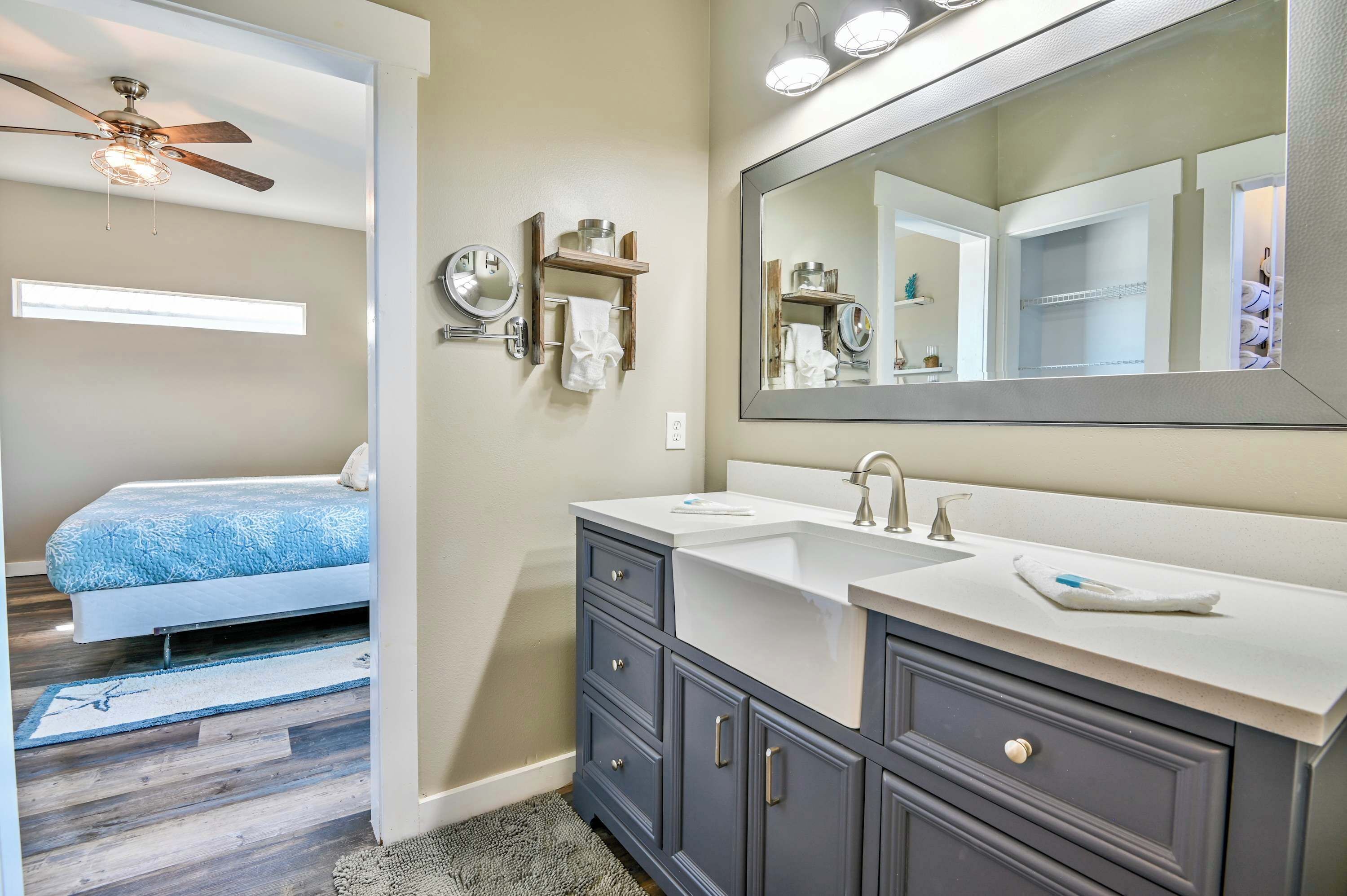 A bathroom with two sinks, a large mirror, and a ceiling fan.