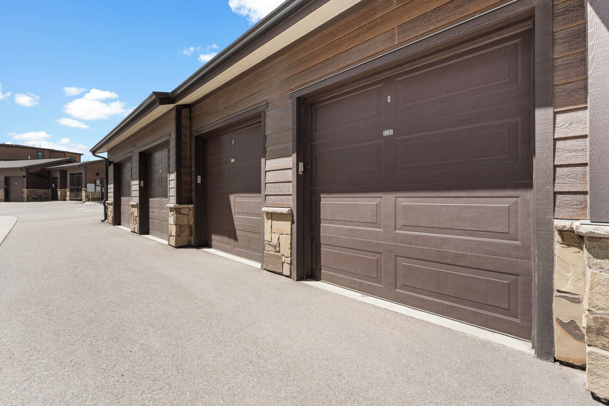 A row of garage doors with stone accents, a clear sky, and a paved driveway.