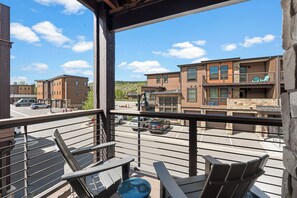 Un balcon avec des chaises, une vue sur une rue animée et des bâtiments en arrière-plan.
