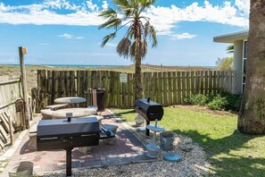 A backyard with a barbecue grill, a table, and a chair.