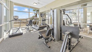 A gym with treadmills, weight machines, and a large window offering a view of the outdoors. - Beachfront Views and Resort Amenities (Orange Beach)