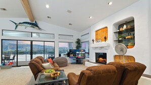 A modern living room with leather sofas, a glass coffee table, a flat-screen TV, and a fireplace.