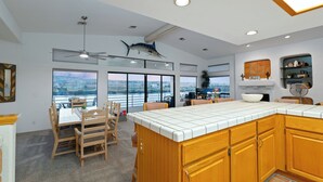 A spacious kitchen with a large island, wooden cabinets, and a view of the city through large windows.