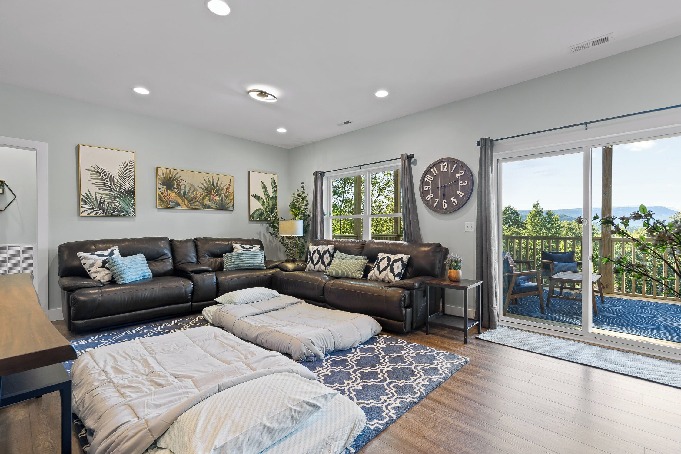 A modern living room with a sectional sofa, a dining table, and a large window with a view.