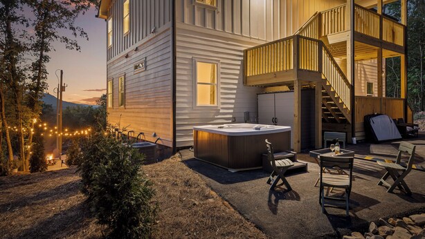 Une maison à deux étages dotée d’un jacuzzi, d’un espace salon extérieur et d’un escalier menant à l’étage supérieur.