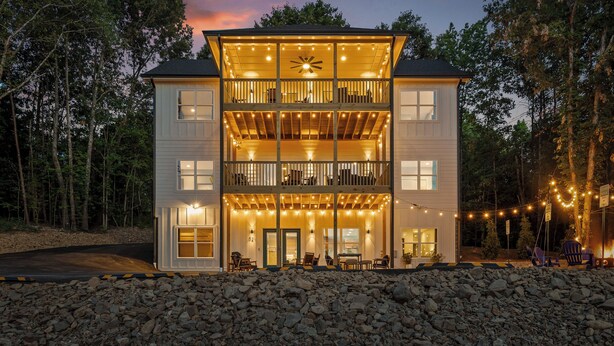 A two-story building with a balcony on the upper floor, a covered outdoor seating area, and string lights.
