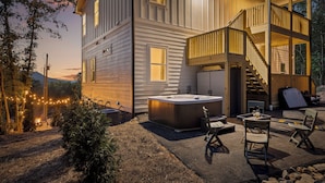 Une maison à deux étages dotée d’un jacuzzi, d’un espace salon extérieur et d’un escalier menant à l’étage supérieur.