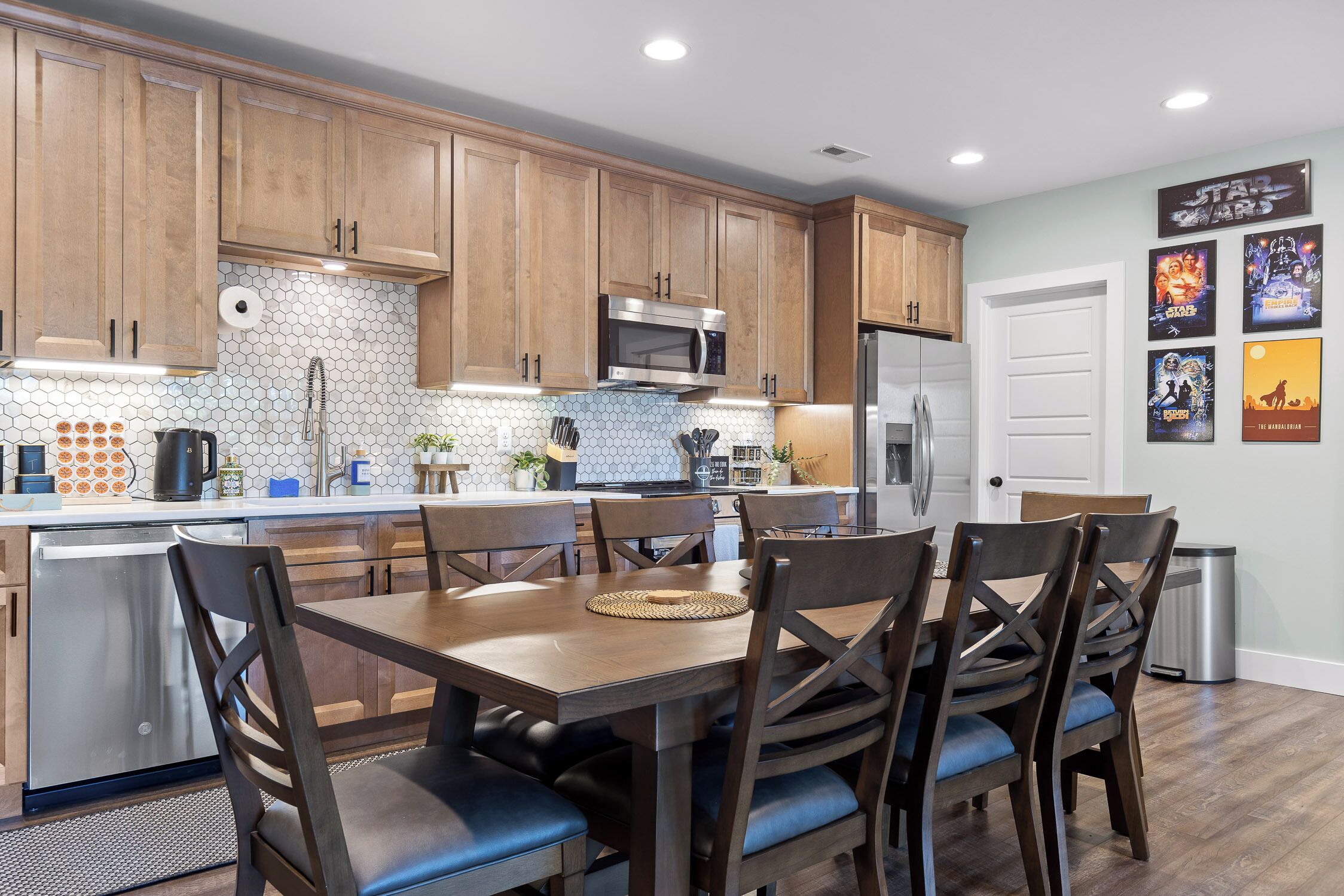 Una cocina moderna con armarios de madera, electrodomésticos de acero inoxidable y un comedor con mesa y sillas de madera.