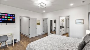 Ein Schlafzimmer mit Bett, Schreibtisch und einem an der Wand befestigten Fernseher, der verschiedene Anwendungen zeigt.