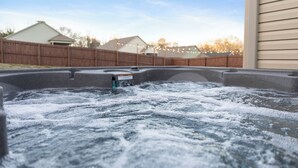 Ein Whirlpool mit Beschriftung, umgeben von einem Holzzaun und Häusern im Hintergrund.