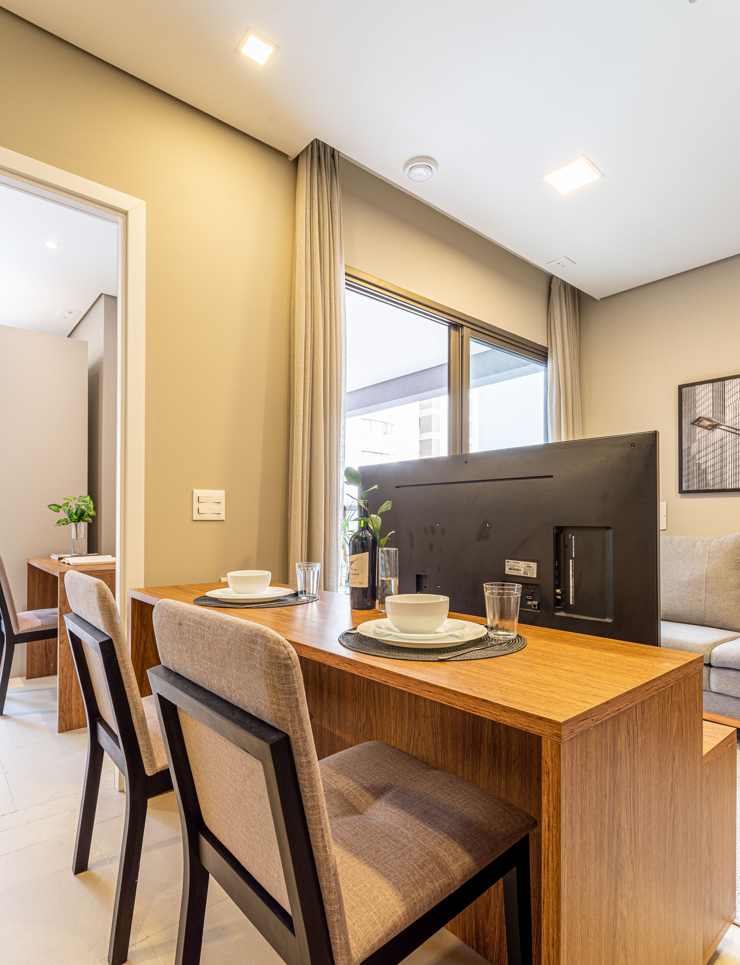 A modern dining area with a wooden table, chairs, and a black TV.