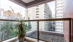 Ein Balkon mit einem Blumentopf, Blick auf eine Baustelle und hohe Gebäude im Hintergrund.