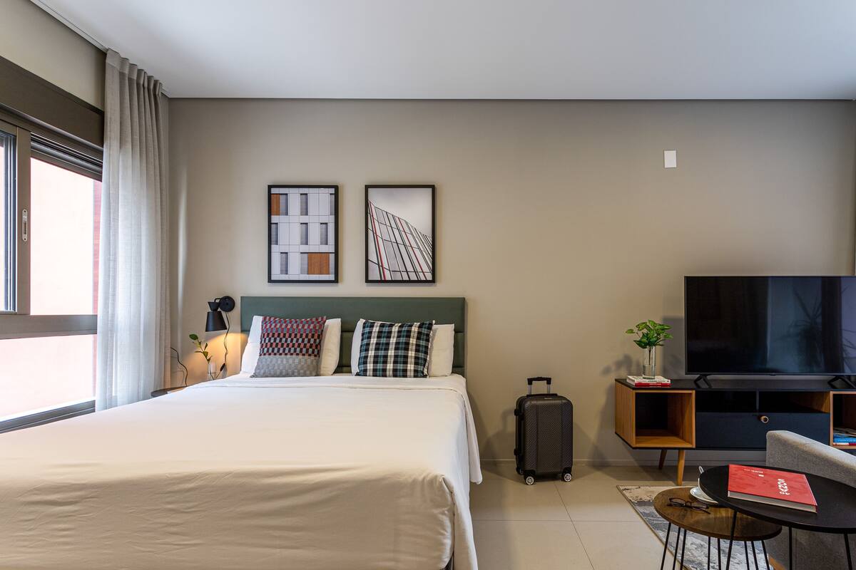 Ein Hotelzimmer mit Bett, Fernseher, Schreibtisch und Stuhl.