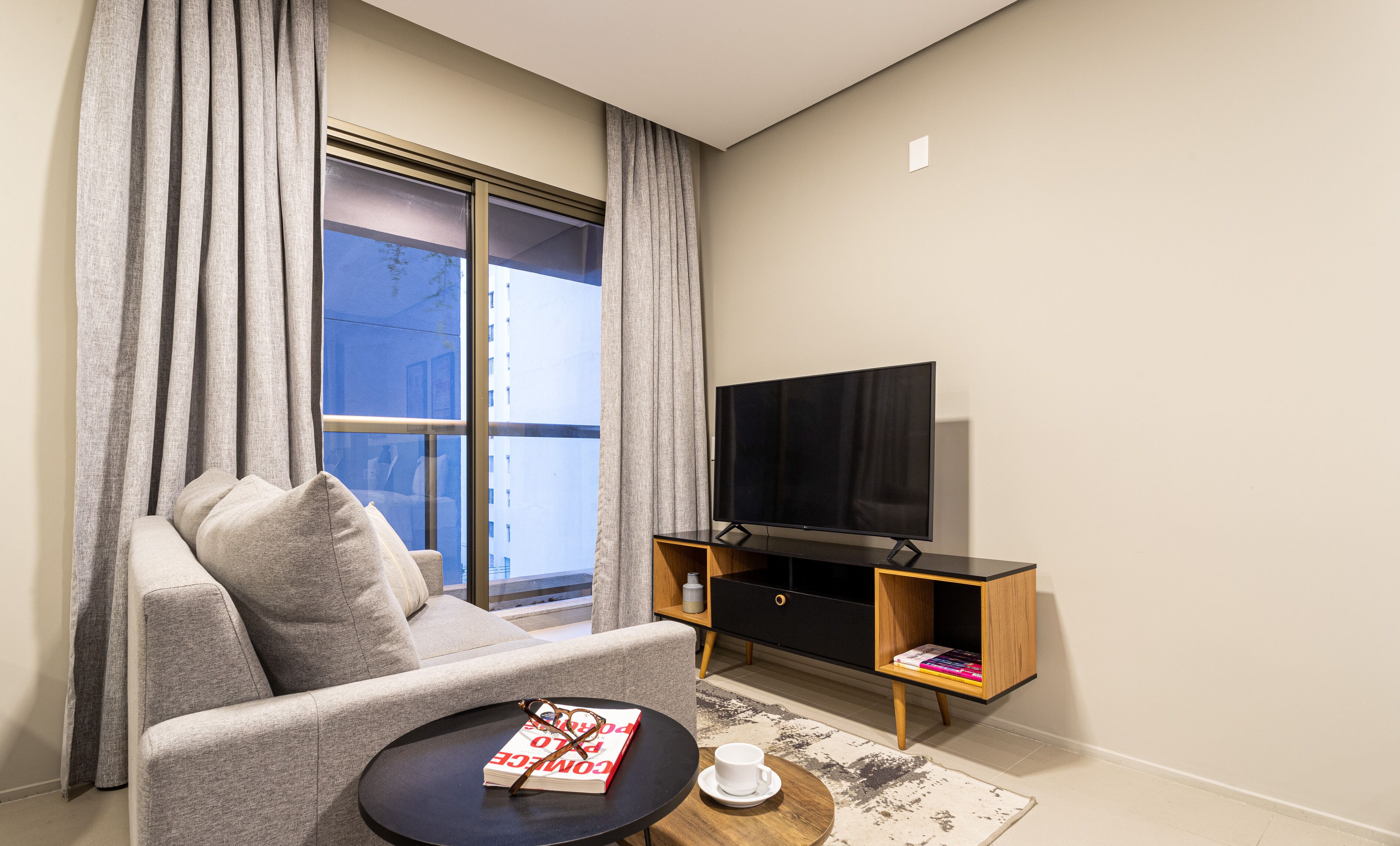 Een moderne woonkamer met een bank, een salontafel, een televisie en een boekenkast.