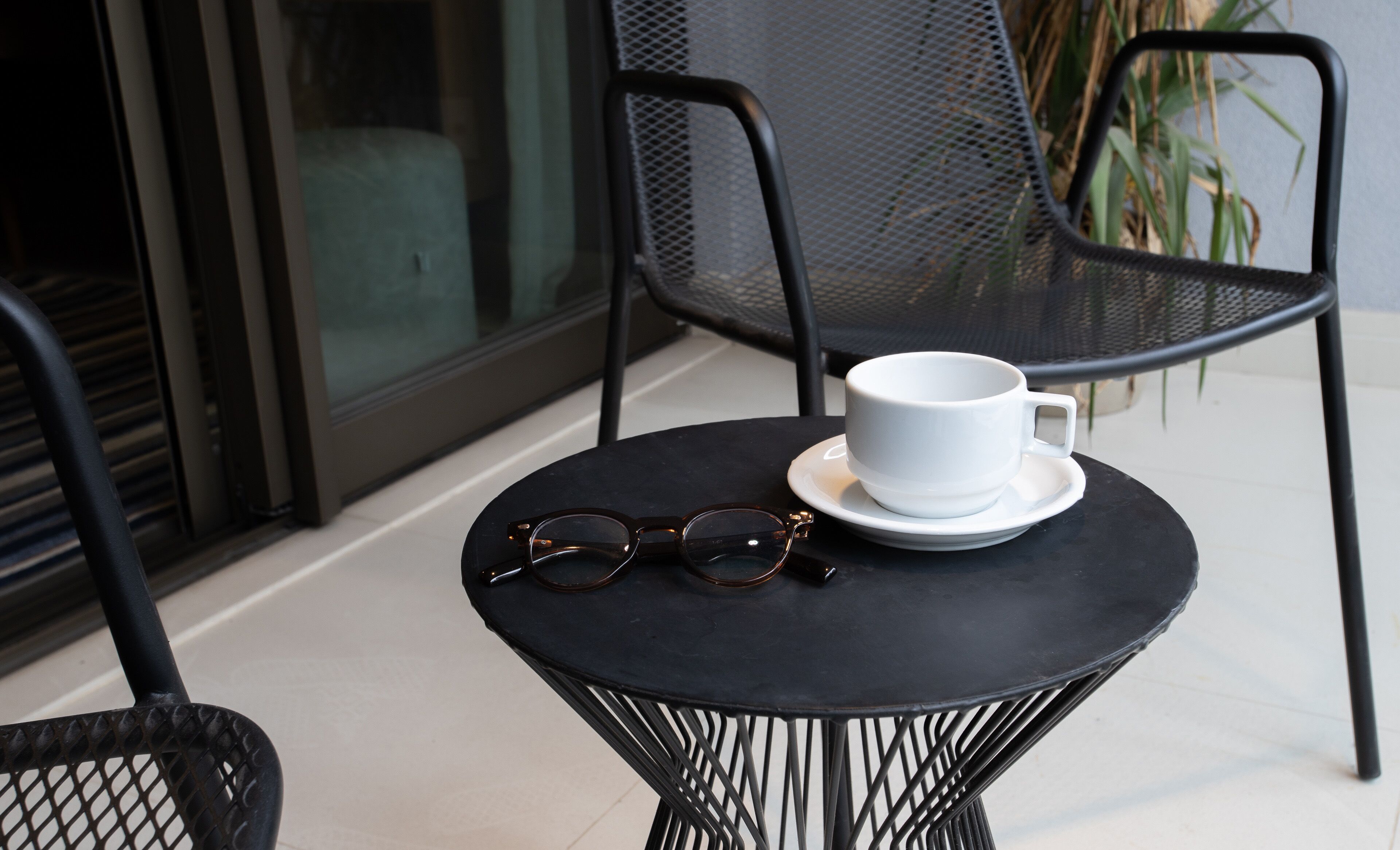 Ein kleiner runder Tisch mit einer weißen Tasse, einem Untertasse und zwei Gläsern.
