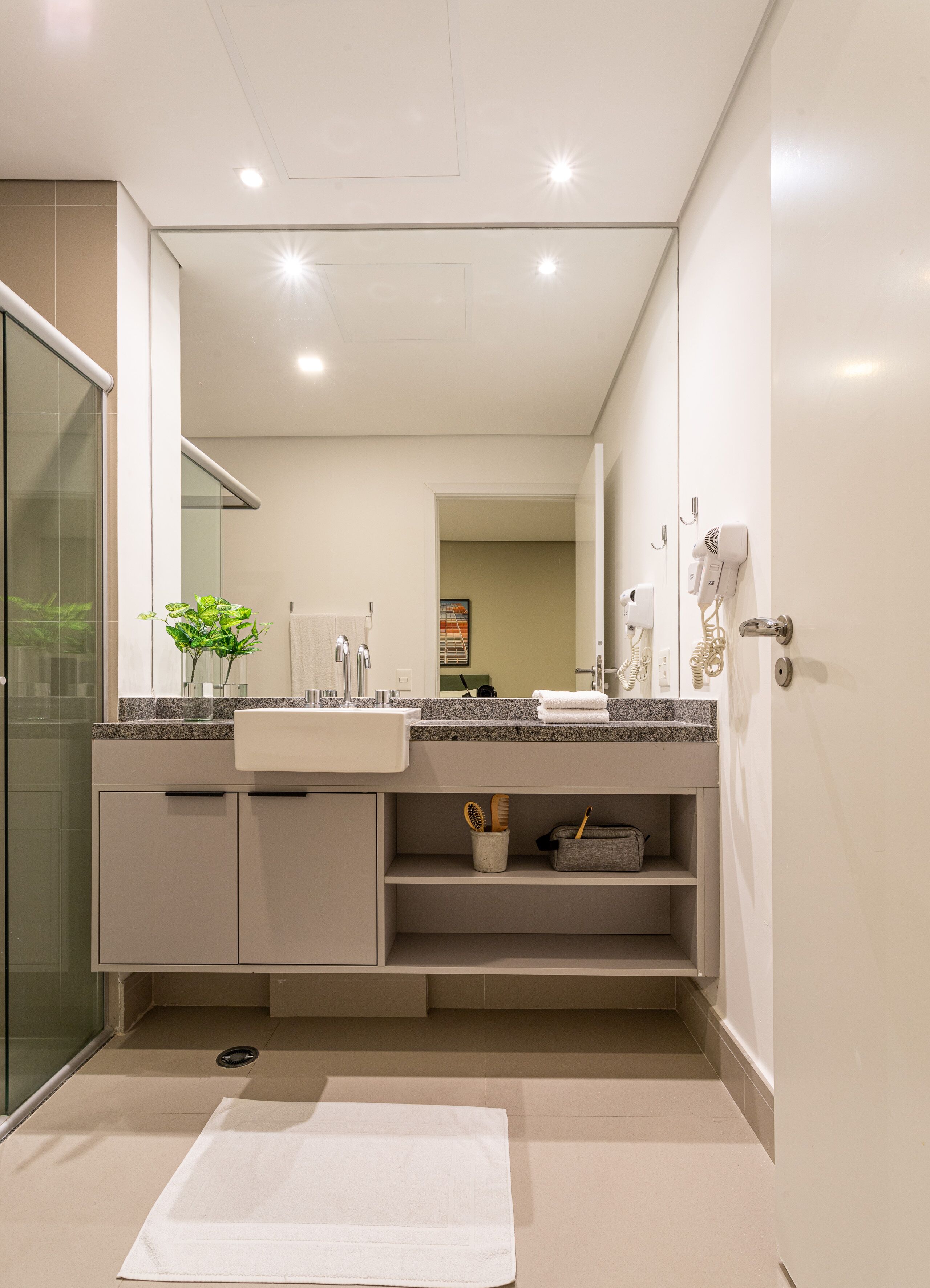 Un bagno moderno con uno specchio grande, un lavandino e uno spazio doccia.
