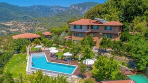 A hotel with a swimming pool, multiple guest rooms, and a mountainous backdrop. - Avena Mountain Hotel (Alanya)