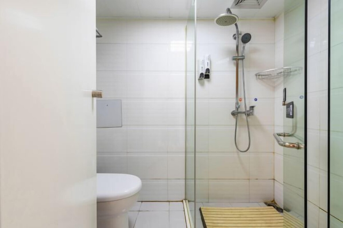 A small, modern bathroom with a glass shower enclosure, a toilet, and a towel rack.