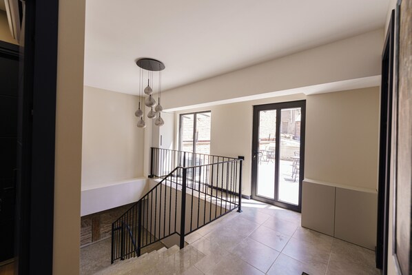 A spacious interior with a staircase, a modern light fixture, and a view through a glass door to an outdoor area. - ARAKI Sololaki (Tbilisi)