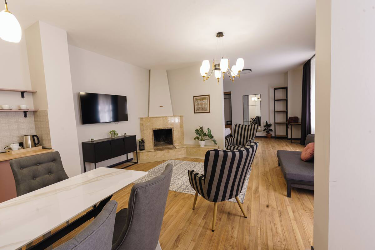 Una sala de estar moderna con chimenea, un comedor con una mesa de mármol y sillones a rayas.