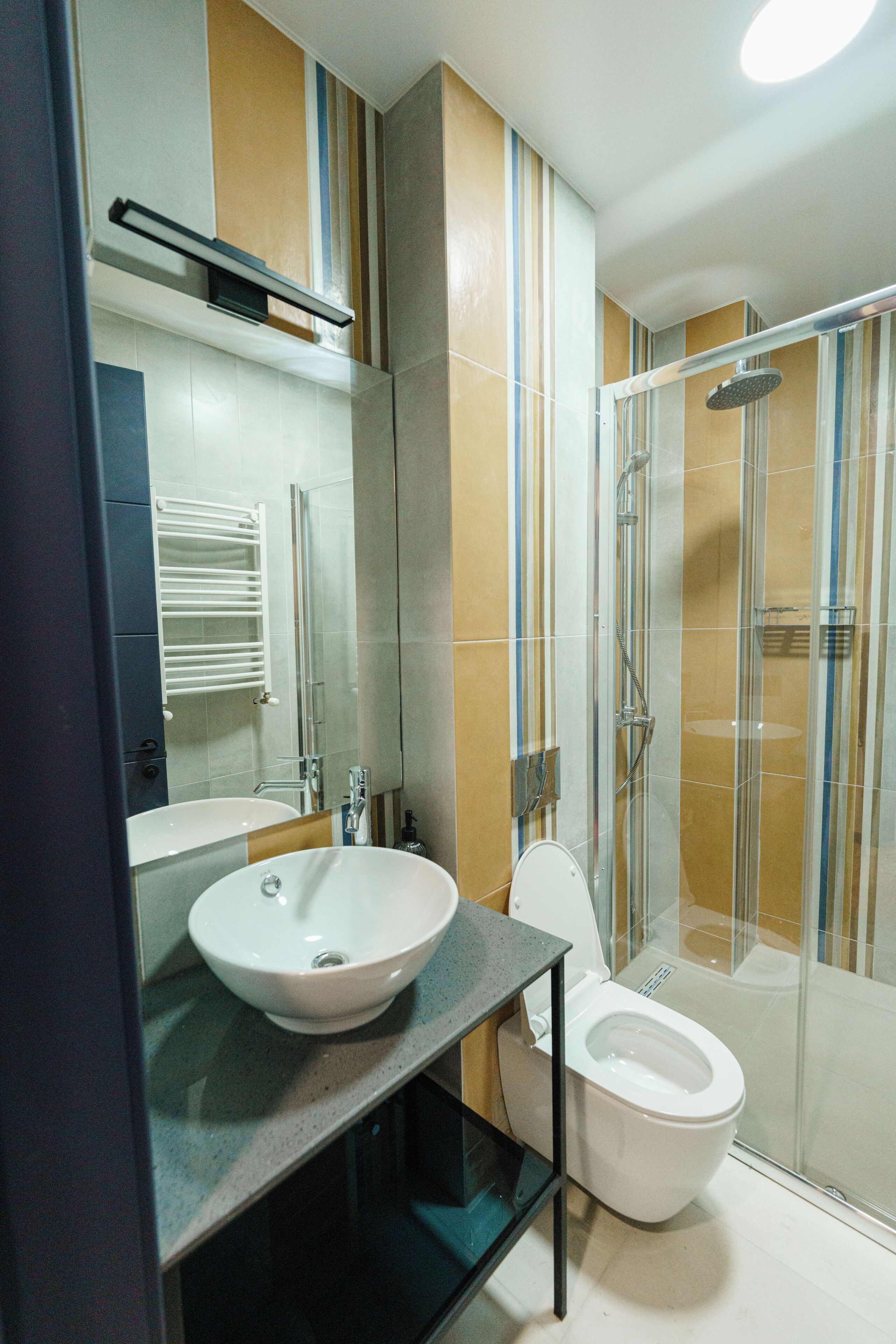 Een moderne badkamer met een douchecabine van glas, een witte wastafel en een toilet.