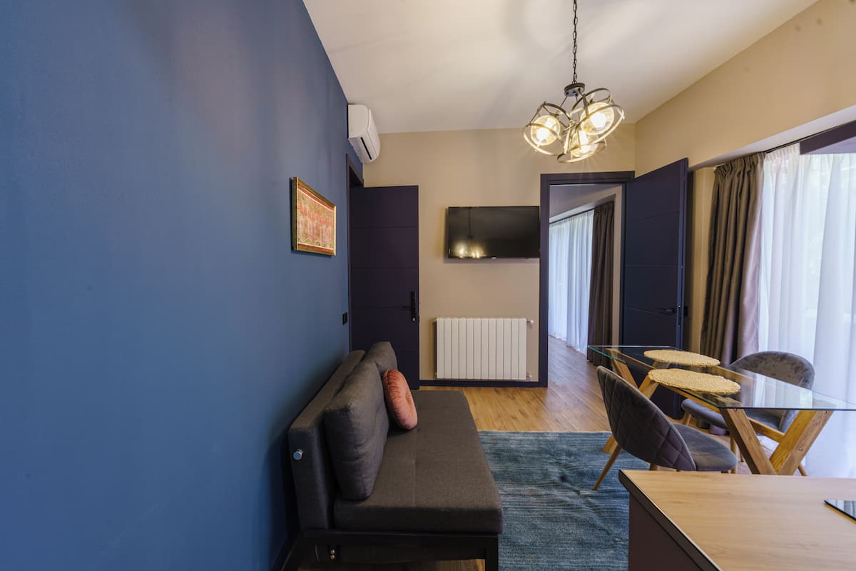 Una sala de estar moderna con un sofá, una mesa de comedor de vidrio y un televisor montado en la pared.