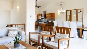 A modern living room with a sofa, wooden chairs, a coffee table, and a dining area with a table and chairs. - Zenzontle - Two Level Condo Beach Facing(30 Steps) (Bucerías)