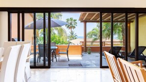 A room with a view of a patio area, including a table, chairs, and a large umbrella. - Zenzontle - Two Level Condo Beach Facing(30 Steps) (Bucerías)