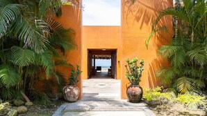 A pathway leading to a building with an open entrance, surrounded by lush greenery and potted plants. - Zenzontle - Two Level Condo Beach Facing(30 Steps) (Bucerías)