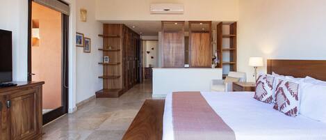 Una habitación de hotel con cama, escritorio, silla, televisor y armario.