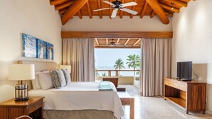 Une chambre avec un lit, une télévision, un bureau et un balcon donnant sur des palmiers.
