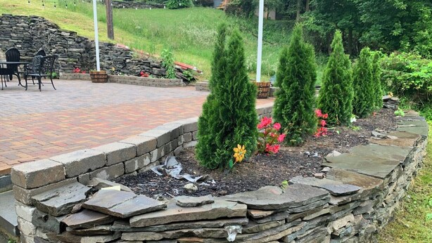 A stone retaining wall with a brick patio and potted plants. - Charming 4-bedroom house with WiFi and AC in fantastic Hawley (Hawley)