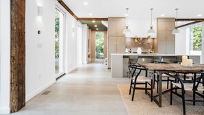 Una cocina moderna con una isla central, iluminación colgante y vistas al exterior.