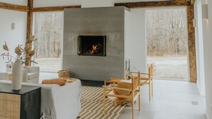 Un interior moderno con vigas de madera a la vista, una chimenea, un sofá y un comedor.