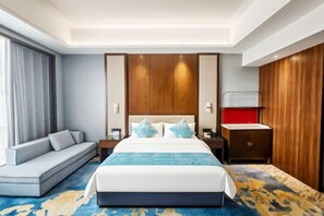 A hotel room with a bed, a sofa, a nightstand, and a wooden wardrobe. - Shizuishan Jinguan Hotel (Shizuishan)