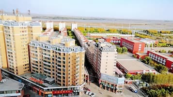 A multi-story residential building with a central courtyard, surrounded by commercial buildings and a parking area.