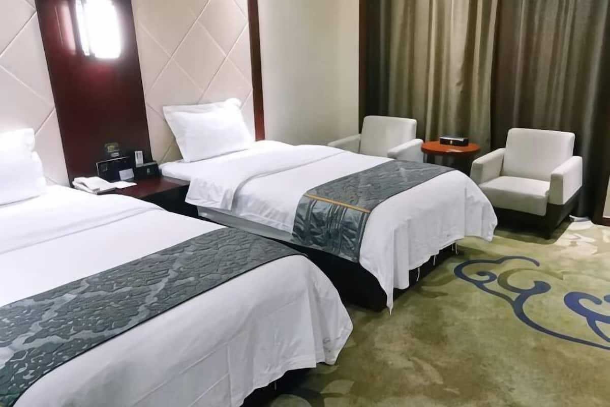 A hotel room with two beds, a nightstand, a chair, and a carpet with a blue design.