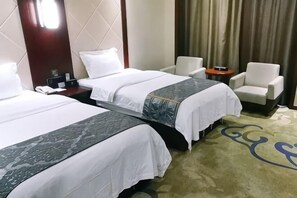 Ein Hotelzimmer mit zwei Betten, einem Nachttisch, einem Sessel und einem Teppich mit blauem Muster.